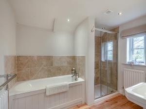 a bathroom with a tub and a shower and a sink at Swallow Cottages, No 1 - Uk46811 in Thurgarton