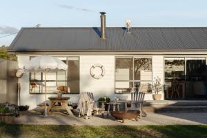 a white house with chairs and an umbrella at Lobster Pot Cabin in Coles Bay +18 photos