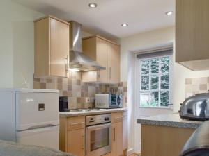 a kitchen with wooden cabinets and a white appliance at Endless Summer Cottage in Camelford
