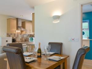 a dining room table with a bottle of wine and chairs at Endless Summer Cottage in Camelford