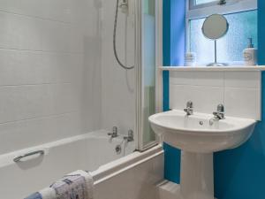 a white bathroom with a sink and a bath tub at Endless Summer Cottage in Camelford +9 photos