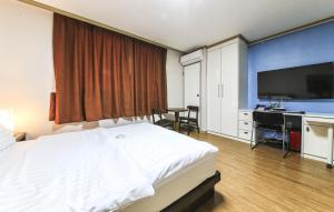 Dormitorio con cama, escritorio y TV en Crystal Residence Hotel en Daejeon