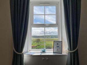 a window with blue curtains and a sign in front of it at Pine Cottage - Dalcross in Dalcross