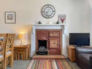 a living room with a fireplace and a clock on the wall at Pine Cottage - Dalcross in Dalcross