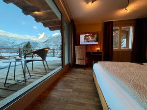 a bedroom with a bed and a balcony with a view at Alpenlodge in Zermatt
