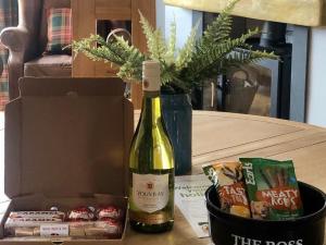 a bottle of wine sitting next to a box of snacks at Clarinnes Cottage in Rowardennan