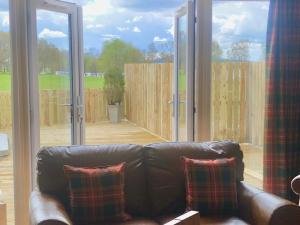 a leather couch in a living room with sliding glass doors at Clarinnes Cottage in Rowardennan