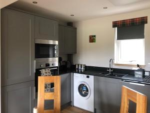 a kitchen with a washing machine and a washer at Clarinnes Cottage in Rowardennan +8 photos
