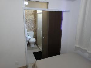 a small bathroom with a toilet and a bed at Ondina Praia Apartamento in Salvador