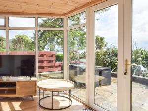 a living room with sliding glass doors and a tv at Southcroft Lodge in Whiting Bay