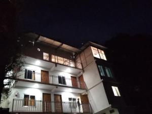 a building with two people on a balcony at night at Mount aura stay & Dine in Kanatal
