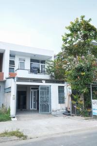 a white house with a gate and a tree at Tâm An Hotel 2 in Nhơn Trạch