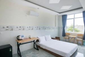a bedroom with a bed and a table and a window at Tâm An Hotel 2 in Nhơn Trạch