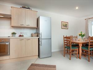 a kitchen with a refrigerator and a table with chairs at Gull Cottage in Falmouth