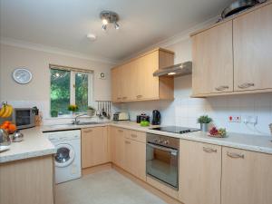 a kitchen with white appliances and wooden cabinets at Gull Cottage in Falmouth