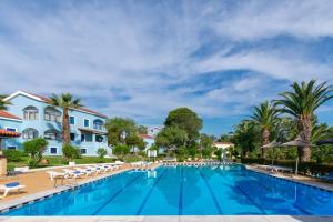 a swimming pool with lounge chairs and a resort at Gouvia bay Serenity in Gouvia