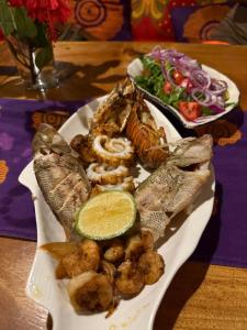 a plate of food with fish and shrimp and a salad at Carpe Diem Nungwi in Nungwi +59 photos