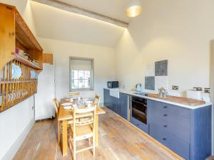 a kitchen with blue cabinets and a table with chairs at Apartment At Llanerchydol Hall in Welshpool +18 photos
