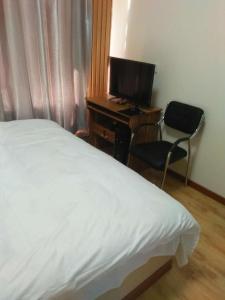 Schlafzimmer mit einem Bett und einem Schreibtisch mit einem Computer in der Unterkunft Xinming Fashion Hotel in Yanji
