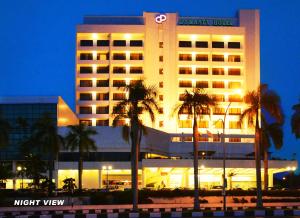 a night view of a hotel with palm trees in front of it at Dynasty Hotel Miri in Miri