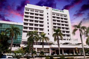 a large white building with palm trees in front of it at Dynasty Hotel Miri in Miri