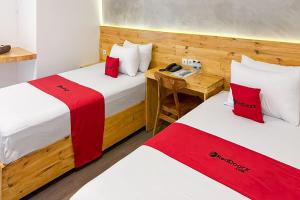 two beds in a room with red and white pillows at RedDoorz @ Klaten City in Klaten