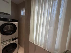 a bathroom with a microwave and a window with curtains at RETLAV LUXURY Apartment in San Donato Milanese