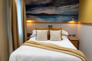 a bedroom with a bed with a painting on the wall at Albert Hotel in Kirkwall