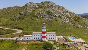 a lighthouse on the side of a hill with a building at Hotel Boutique Faro Silleiro in Baiona