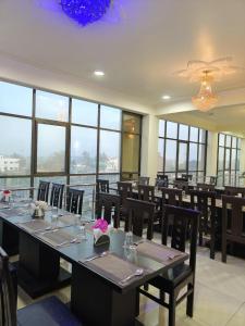 a dining room with tables and chairs and windows at J P PALACE in Kushinagar