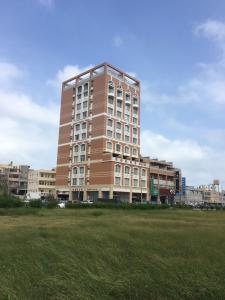 a tall building with a grass field in front of it at Happy Hotel in Magong