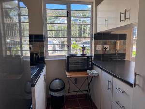 a kitchen with a microwave and a stove in it at Outspan Lodge in Fish Hoek