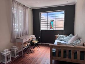 a bedroom with a bed and a desk and a window at Outspan Lodge in Fish Hoek