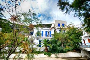 a white building with blue windows and trees at Plumeria Flowery in Agios Kirykos