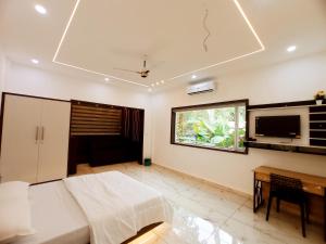 a bedroom with a bed and a desk and a television at Chikkary's Inn in Munnar
