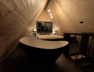 a bath tub in a room with a bed at ALTURA Chalet in Muntele Băişorii