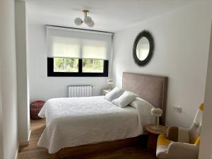 a white bedroom with a bed and a mirror at Brisa Marela in Sanxenxo