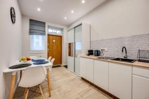 a kitchen with white cabinets and a table and chairs at Central Platinum Apartments 26 in Rybnik