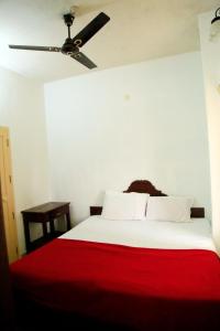 a white bed with a red blanket and a ceiling fan at Avalan Resort Homestay in Thekkady