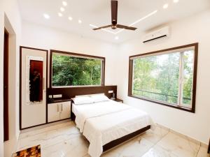 a bedroom with a bed and two large windows at Chikkary's Inn in Munnar
