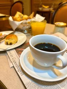 a cup of coffee on a table with a plate of food at Hôtel de Varenne in Paris