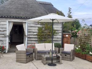 a patio with two chairs and an umbrella at Sheepwash Barn in Freshwater