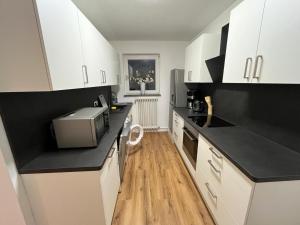 a kitchen with white cabinets and black counter tops at City Apartment Schillerstraße in Wilhelmshaven +3 photos