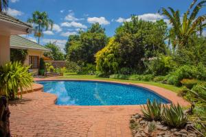a swimming pool in a yard with a brick walkway and trees at 12 FLEETWOOD in Harare