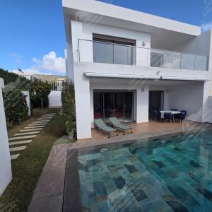 a villa with a swimming pool in front of a house at Serenity Sea Villa Taghazout Bay Amda in Taghazout