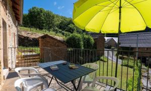 a table and chairs with a yellow umbrella on a balcony at Gîte de Malavals in Castelnau-de-Mandailles