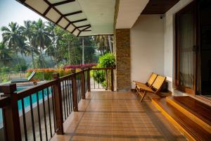 a balcony of a house with a bench and a pool at Pollachi Riverhouse, A CGH Earth Saha experience in Pollāchi