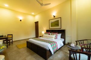 a bedroom with a bed and a table and chairs at Pollachi Riverhouse, A CGH Earth Saha experience in Pollāchi +49 photos