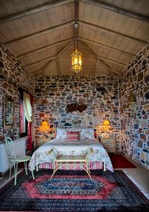 Un dormitorio con una cama y una pared de piedra. en Olive Grove Villas, en Áfissos