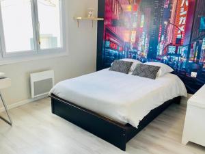 a bedroom with a large bed with a painting on the wall at La Maison Nikaïa in Narbonne +11 photos